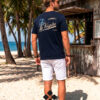 hombre vistiendo camiseta algodón azul marino de La Vespita en kiosko de playa paradisiaca