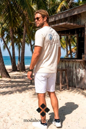 hombre vistiendo camiseta algodón beige de La Vespita en kiosko de playa paradisiaca
