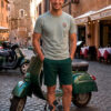 Hombre con camiseta de algodón verde con dibujo en el pecho junto a una moto vespa